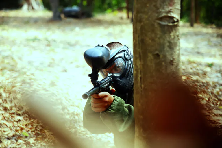 Paintball Spieler hinter dem Baum